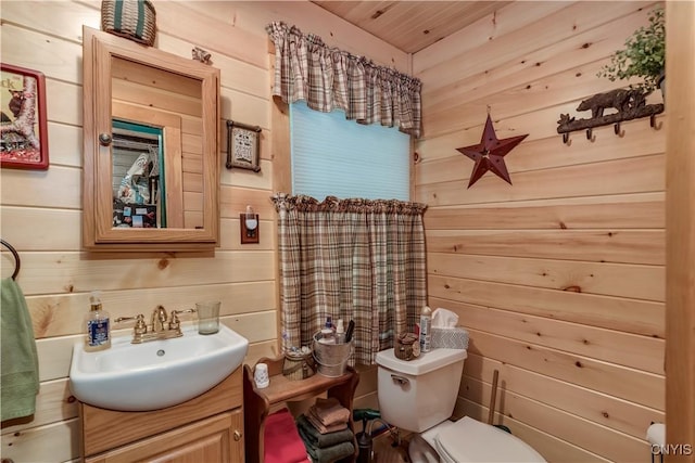 bathroom featuring wooden walls, toilet, vanity, and wood ceiling