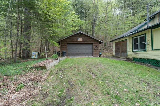 view of yard featuring a detached garage, an outdoor structure, and a wooded view