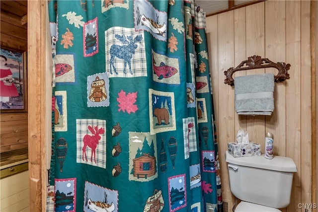bathroom featuring wooden walls, toilet, and water heater