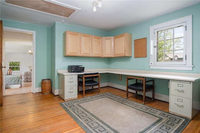 office featuring attic access, built in study area, light wood finished floors, and plenty of natural light