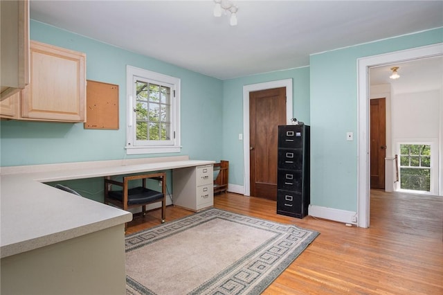 office space featuring light wood-type flooring, healthy amount of natural light, and baseboards