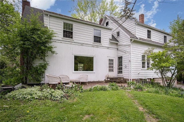 back of property with a chimney and a yard