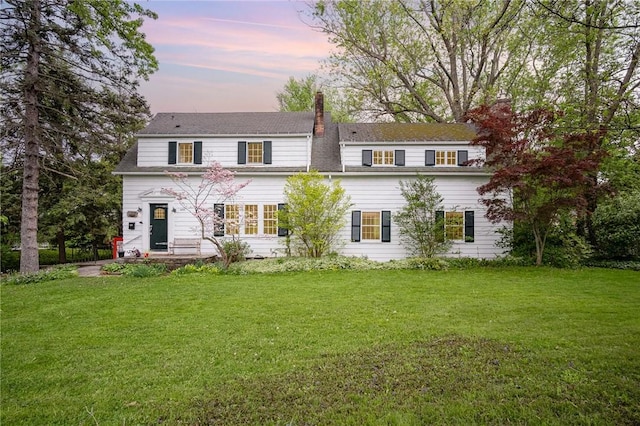 view of front facade featuring a chimney and a lawn