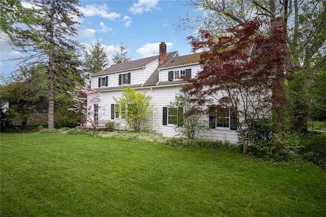 rear view of house with a chimney and a yard