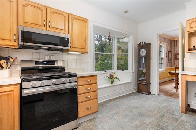 kitchen with stainless steel appliances, light countertops, backsplash, crown molding, and wainscoting
