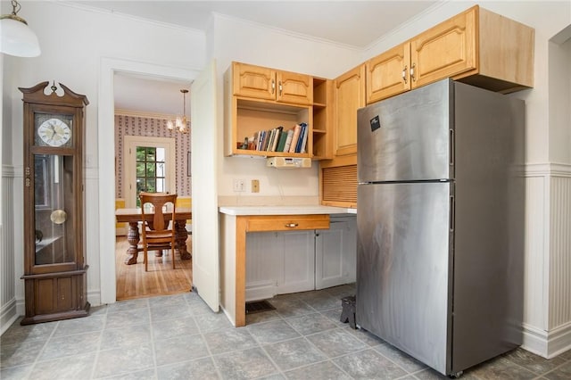 kitchen featuring freestanding refrigerator, ornamental molding, light countertops, a chandelier, and light brown cabinetry