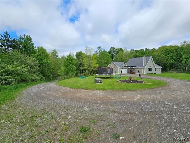 437 Nye Rd, Virgil, NY 13045 - view of front of house with a trampoline, dirt driveway, a front lawn, a chimney, and a forest view