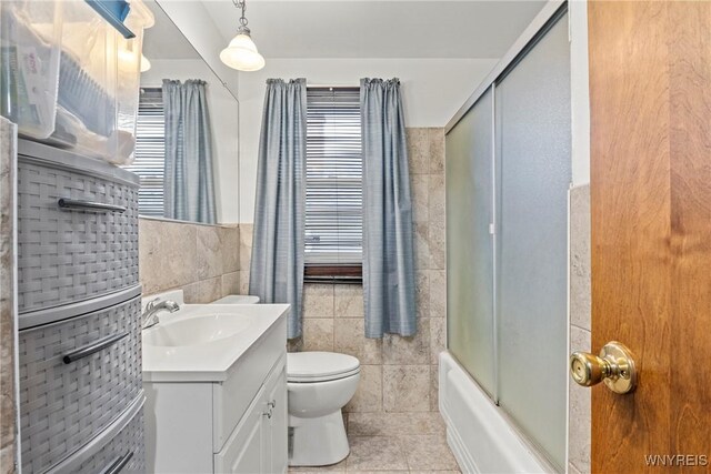 152 Nicholson St, Buffalo, NY 14216 - full bathroom with tile walls, vanity, toilet, tile patterned floors, and bath / shower combo with glass door