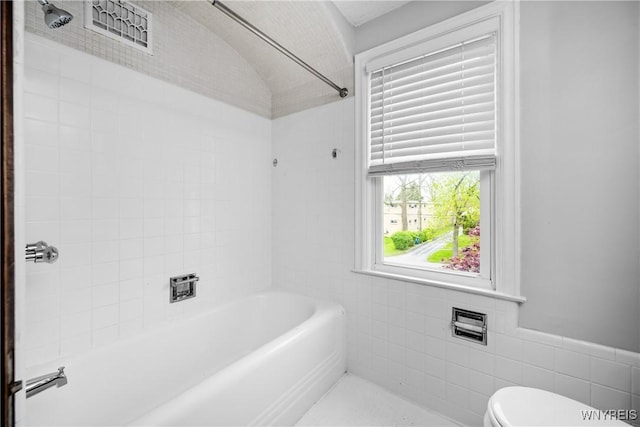 bathroom with toilet, tile walls, and shower / bathtub combination
