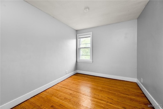 unfurnished room featuring baseboards, a smoke detector, and wood finished floors