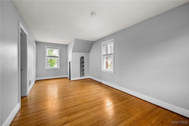 additional living space with light wood-style floors, baseboards, and built in features
