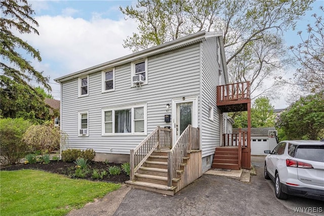 view of front of house with a balcony, cooling unit, an outbuilding, and driveway