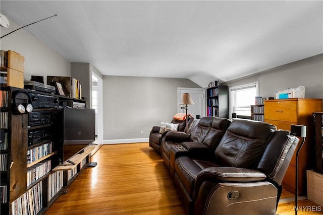 living area featuring lofted ceiling, wood finished floors, and baseboards