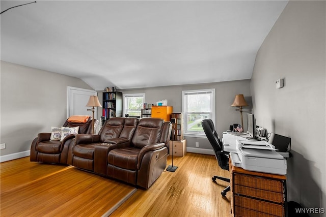 living area with vaulted ceiling, an office area, light wood-type flooring, and baseboards