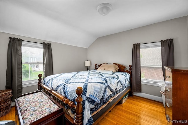 bedroom featuring lofted ceiling, wood finished floors, and baseboards