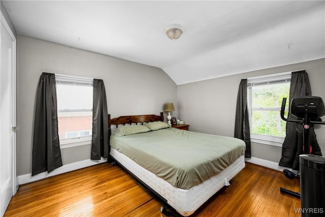 bedroom with wood finished floors, vaulted ceiling, and baseboards