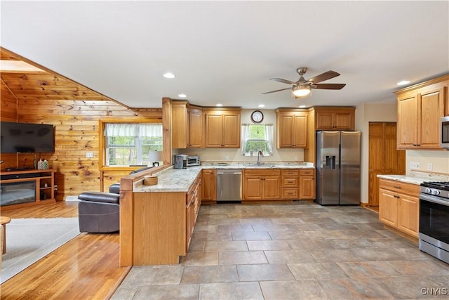 301 Silverstone Rd, Russia, NY 13438 - kitchen with stainless steel appliances, a peninsula, a ceiling fan, recessed lighting, and wood walls