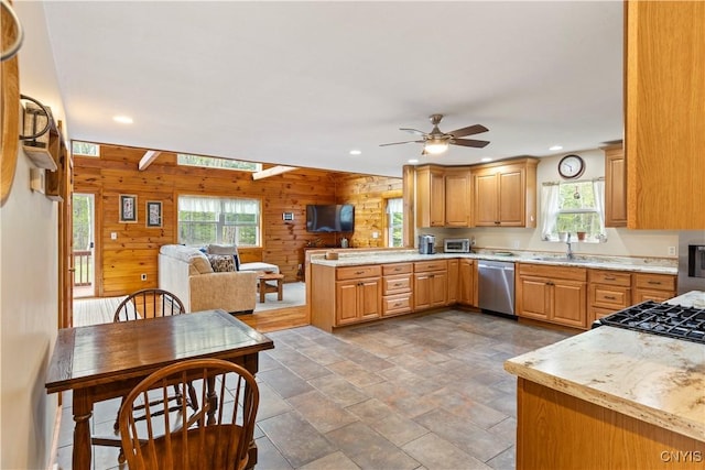 301 Silverstone Rd, Russia, NY 13438 - kitchen featuring stainless steel dishwasher, wooden walls, a ceiling fan, a sink, and a peninsula