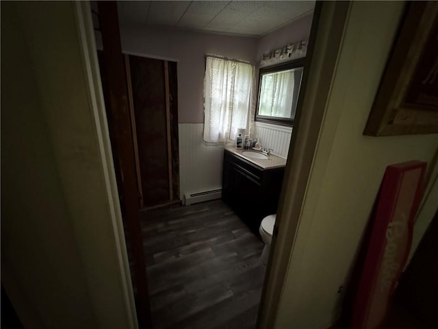 3645 County Highway 12, Kortright, NY 13739 - bathroom featuring a baseboard radiator, wood finished floors, vanity, a wainscoted wall, and toilet