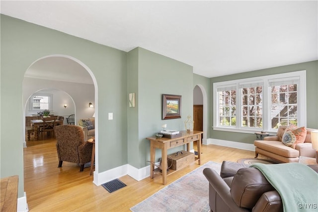 457 Broad St, Oneida-Inside, NY 13421 - living room featuring arched walkways, light wood-style flooring, and baseboards