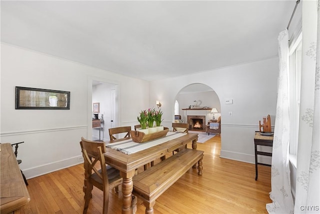 457 Broad St, Oneida-Inside, NY 13421 - dining room featuring a fireplace, light wood-type flooring, baseboards, and arched walkways