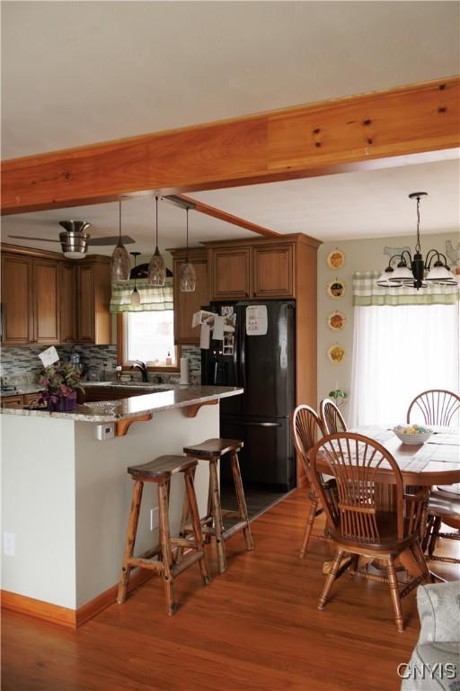 95 Briarcliff Dr, Veteran, NY 14845 - kitchen featuring freestanding refrigerator, beamed ceiling, tasteful backsplash, wood finished floors, and a kitchen breakfast bar