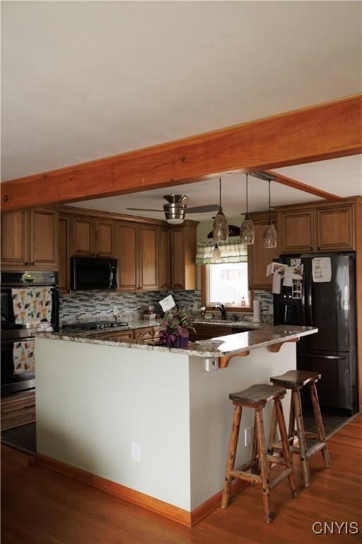 95 Briarcliff Dr, Veteran, NY 14845 - kitchen with black appliances, beamed ceiling, tasteful backsplash, wood finished floors, and a kitchen bar