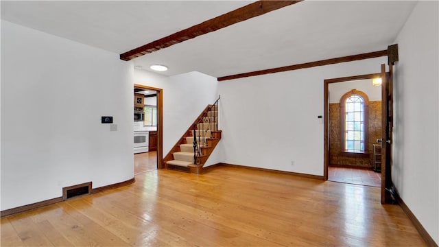 unfurnished living room with light wood-style flooring, stairway, and baseboards