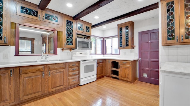 kitchen featuring electric stove, stainless steel microwave, beam ceiling, brown cabinetry, and light wood-type flooring
