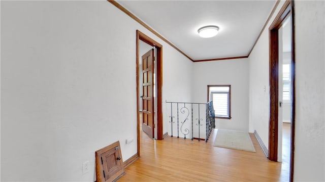 hallway with crown molding, an upstairs landing, light wood-style floors, and baseboards