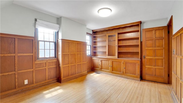 unfurnished room featuring light wood-type flooring and a wainscoted wall