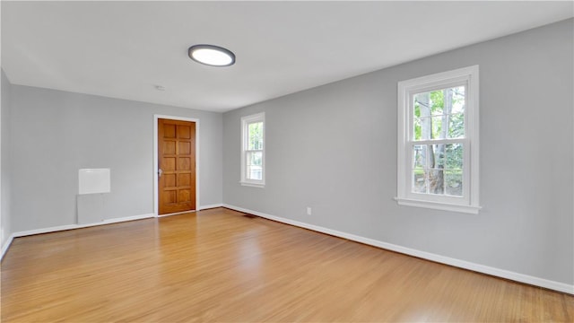 spare room featuring wood finished floors, plenty of natural light, and baseboards