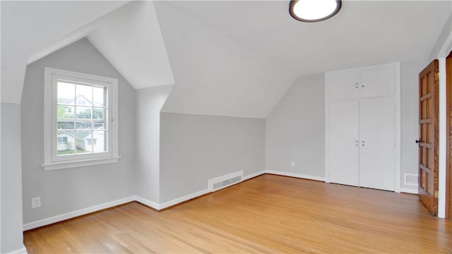 additional living space featuring light wood-style flooring, lofted ceiling, and baseboards