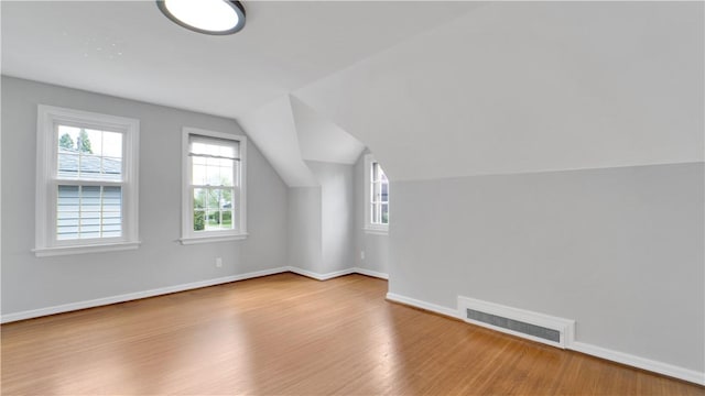 additional living space featuring healthy amount of natural light, wood finished floors, baseboards, and vaulted ceiling