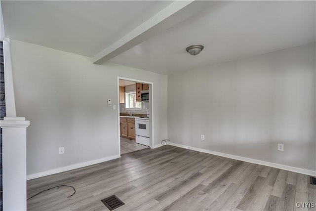 124 Haven St, Watertown-City, NY 13601 - unfurnished living room featuring wood finished floors, baseboards, a sink, and beam ceiling