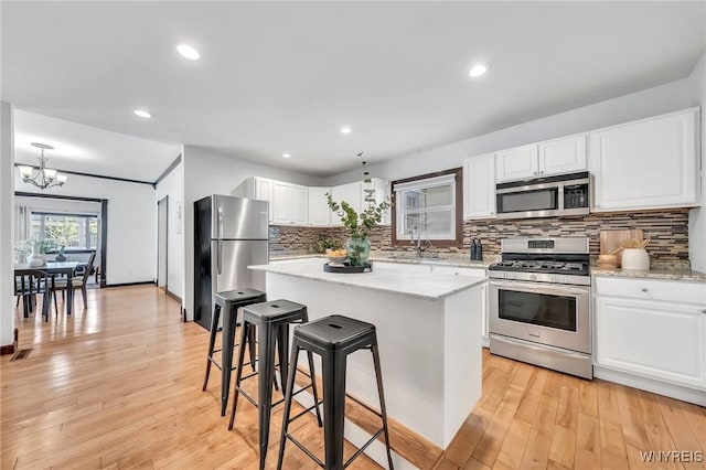 397 14th St, Buffalo, NY 14213 - kitchen featuring appliances with stainless steel finishes, a sink, a chandelier, white cabinetry, and tasteful backsplash