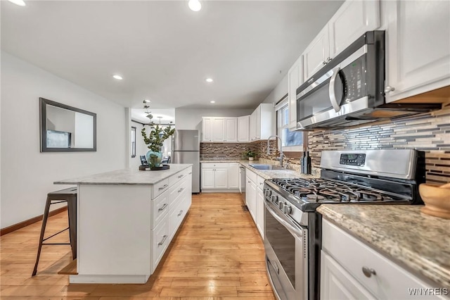 397 14th St, Buffalo, NY 14213 - kitchen with appliances with stainless steel finishes, a sink, light wood-style flooring, a kitchen island, and recessed lighting
