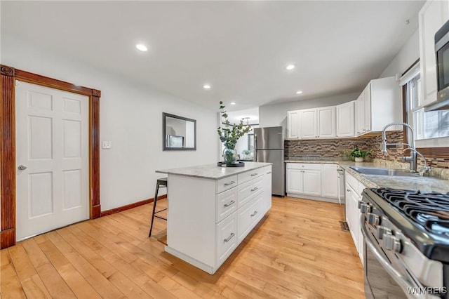397 14th St, Buffalo, NY 14213 - kitchen with appliances with stainless steel finishes, a sink, decorative backsplash, white cabinetry, and a center island