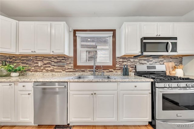 397 14th St, Buffalo, NY 14213 - kitchen featuring appliances with stainless steel finishes, a sink, white cabinetry, decorative backsplash, and light stone countertops