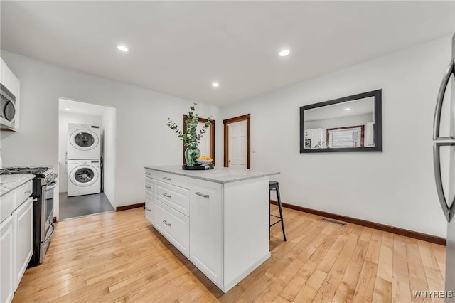 397 14th St, Buffalo, NY 14213 - kitchen with appliances with stainless steel finishes, stacked washer and clothes dryer, a breakfast bar area, white cabinets, and recessed lighting