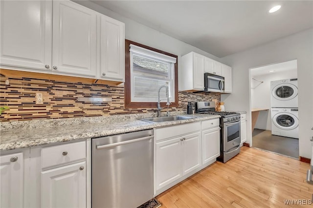 397 14th St, Buffalo, NY 14213 - kitchen featuring stainless steel appliances, stacked washing machine and dryer, a sink, white cabinets, and light wood finished floors