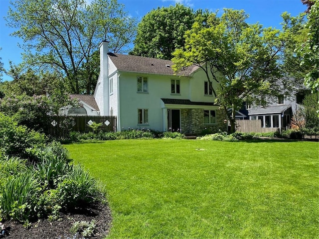 back of house with a chimney, stone siding, and stucco siding