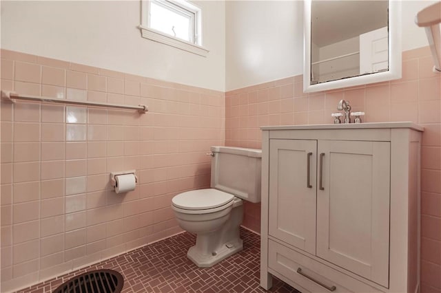 bathroom featuring tile walls, toilet, vanity, wainscoting, and tile patterned floors