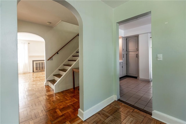 hall with arched walkways, stairs, and baseboards