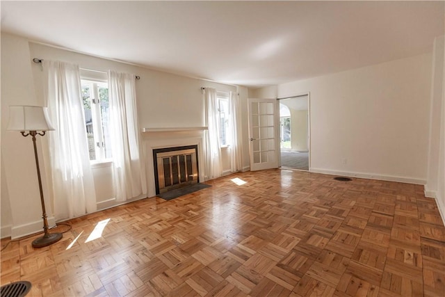 unfurnished living room with a fireplace with flush hearth, healthy amount of natural light, and baseboards