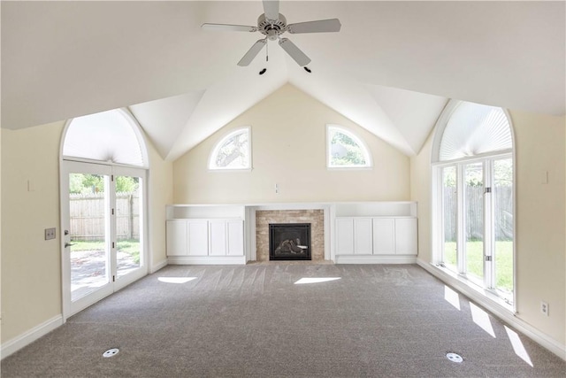 unfurnished living room with carpet flooring, plenty of natural light, ceiling fan, a fireplace with flush hearth, and lofted ceiling