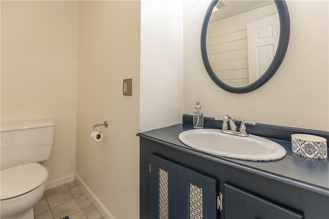 half bath with toilet, vanity, tile patterned flooring, and baseboards