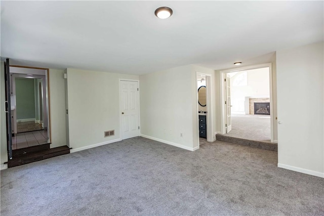 unfurnished living room featuring carpet floors, baseboards, and a fireplace