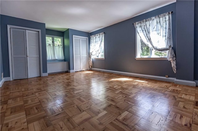 unfurnished bedroom with multiple closets and baseboards