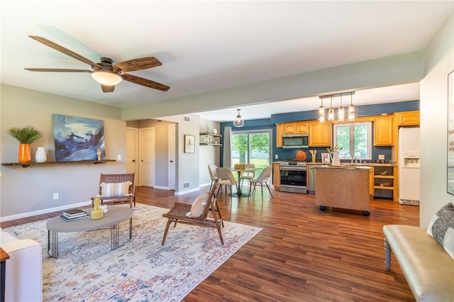 living area featuring dark wood-style floors, baseboards, and ceiling fan